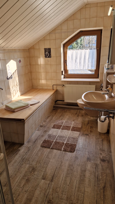 Badezimmer mit Blick auf Waschbecken, Toilette, Schrank und Fenster