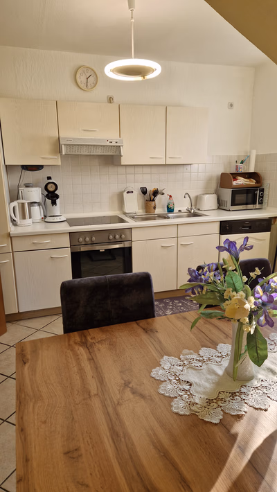 Küche mit Blick auf die Küchenzeile mit Kühlschrank, Wasserkocher, Pad und Filter-Kaffemachiene, Toaster, Mikrowelle, Herd, Backofen und Spülmaschiene