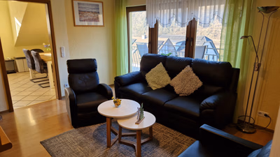 Wohnzimmer der großen Ferienwohnung, Große 3er-Couch, Sofa und 2er-Couch mit kleinem Beistelltisch. Blick zur Küche und auf den Balkon
