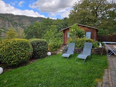 Garten mit Liegen im Vodergrund, im Hintergrund ein kleiner Kräutergarten und der angrenzende kleine Wald