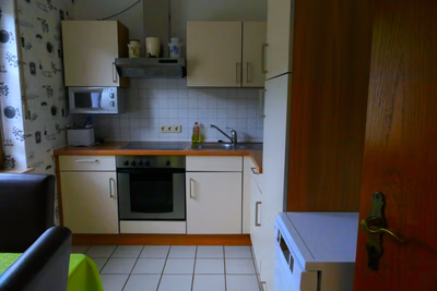 Küche mit Schränken, Kochfeld, Mikrowelle, Toaster, Kühlschrank, Spülmaschiene